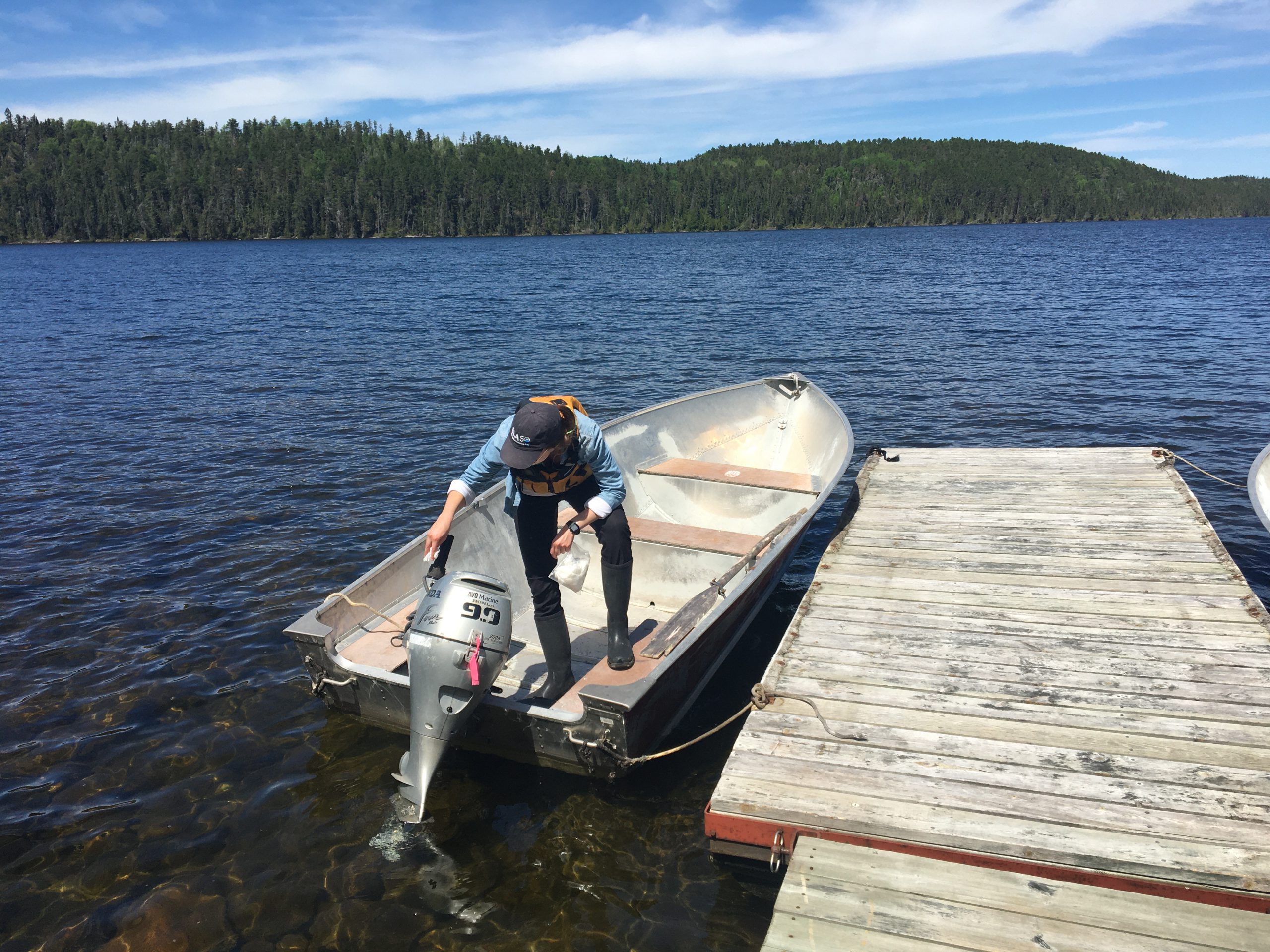 Woman standing in a boat in a freshwater lake in Northern Ontario