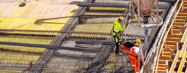 Concrete pouring from crane on construction site.