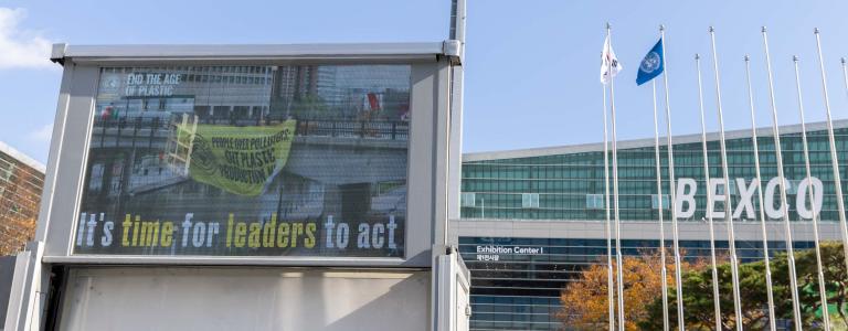 As negotiations continue behind closed doors, signs outside of the venue call for leaders to act and produce a strong treaty to address plastic pollution.