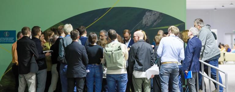 Delegates at COP 29 huddle. In the top right, text reads COP29: It's Time to Act.