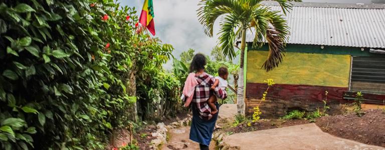 Woman carrying her baby on her hip while walking down a hill in Jamaic