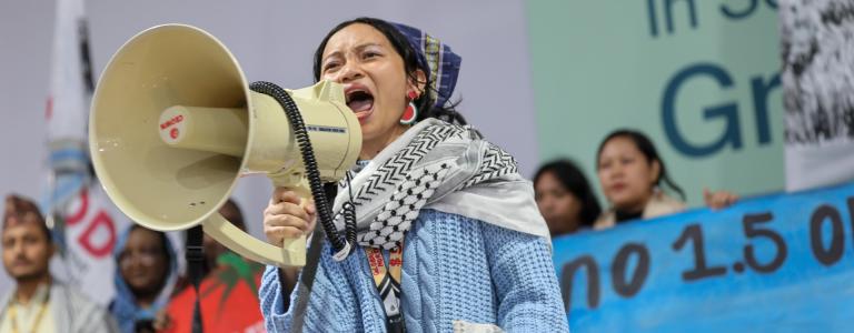 A woman shouts into a loudspeaker at COP29 in Baku, Azerbaijan