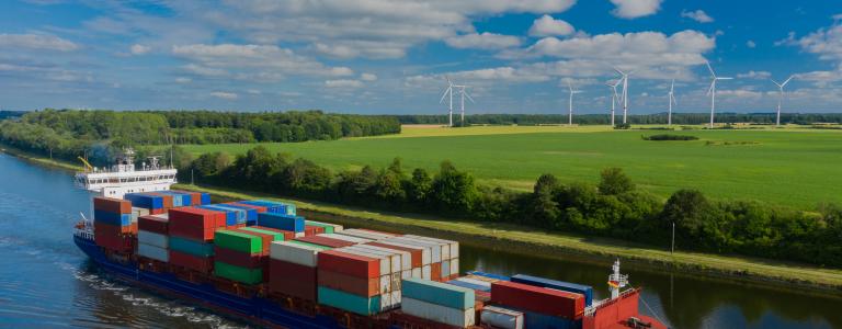 Container ship on the Kiel Canal and windmill on the background