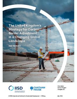 The United Kingdom's Strategy for Carbon Border Adjustment in a Changing Global Landscape report cover showing an engineer in a safety vest and white hard hat reviewing a blueprint at a construction site with cranes in the background.