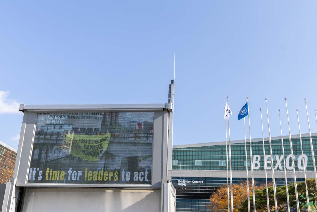 As negotiations continue behind closed doors, signs outside of the venue call for leaders to act and produce a strong treaty to address plastic pollution.