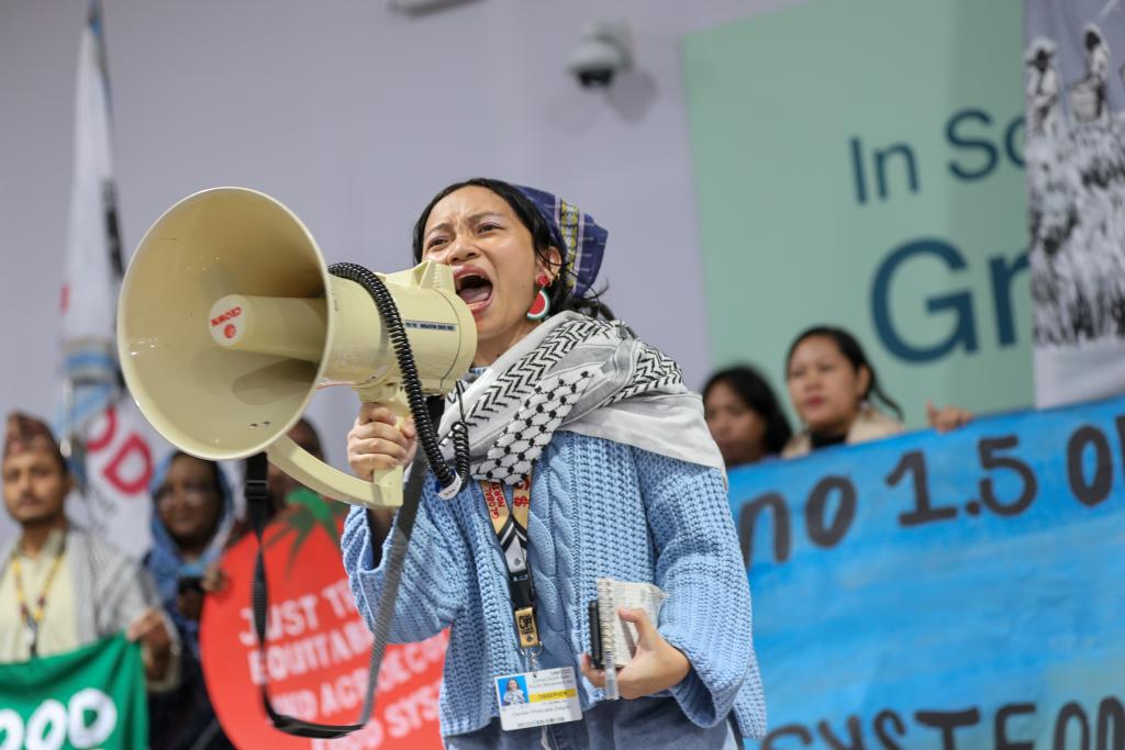 A woman shouts into a loudspeaker at COP 29.