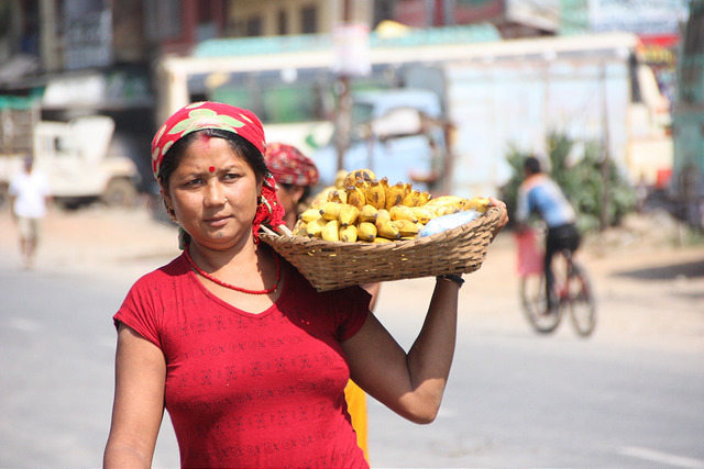 Nepalese woman in red top carrying a basket of banana